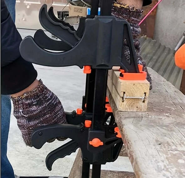 Gloved hand squeezing the trigger clamp onto a workbench rail